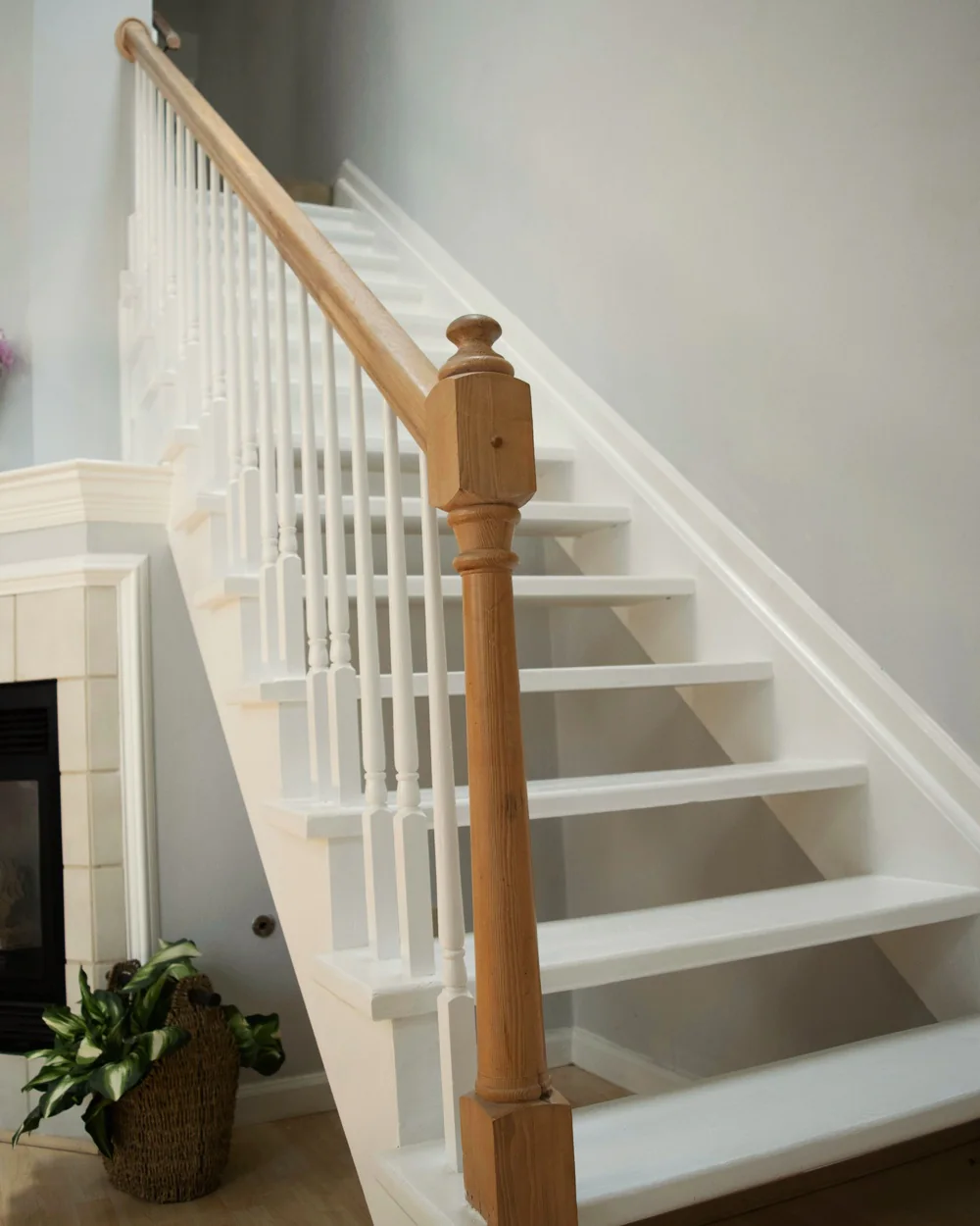 Witte trap met witte spijlen en een houten trappaal