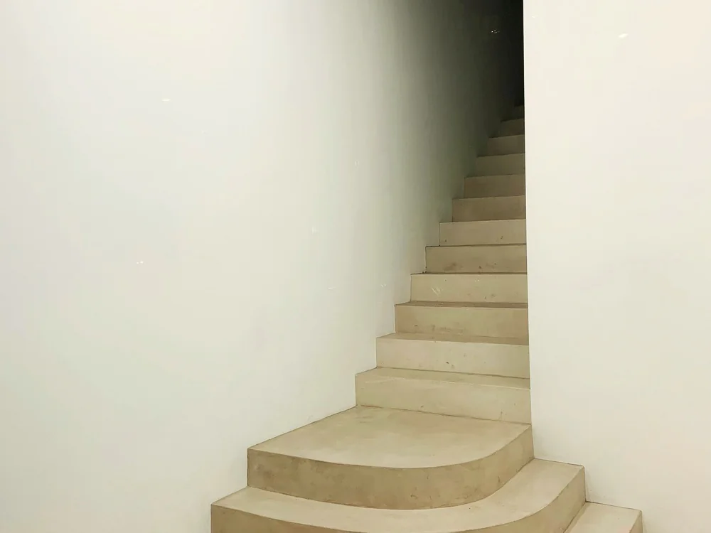 Lichte trap in betonlook met een afgeronde onderste trede